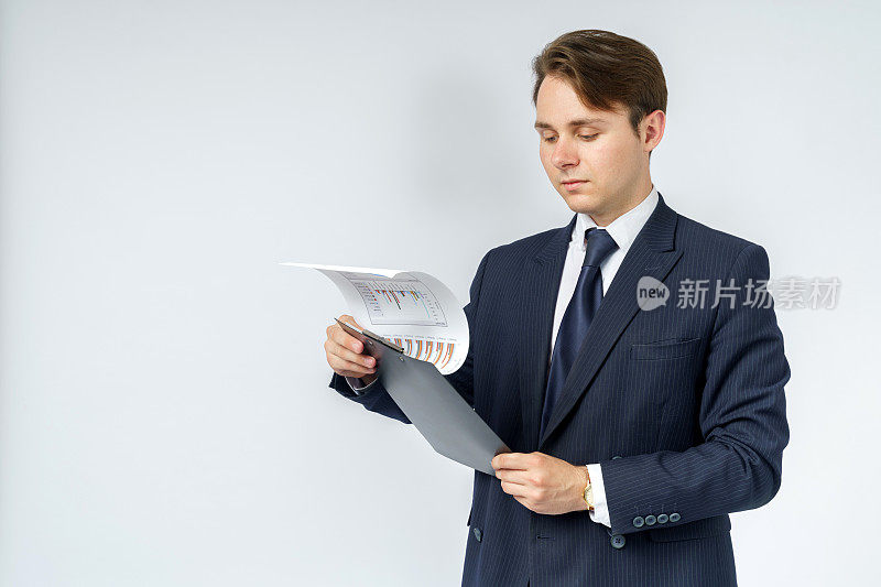 一个穿蓝色西装的商人手里拿着一个文件夹，在白色背景上读着报告。