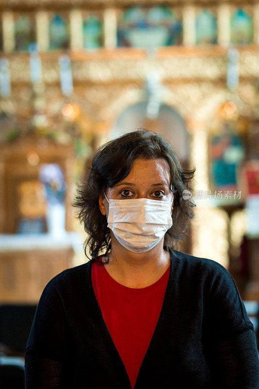 在天主教教堂祈祷的妇女戴着防护面具