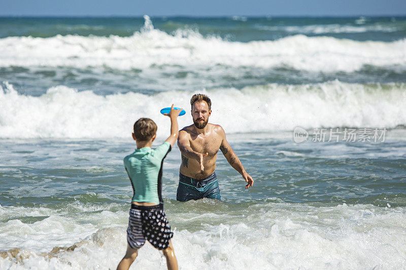 父亲和儿子在海滩玩飞盘