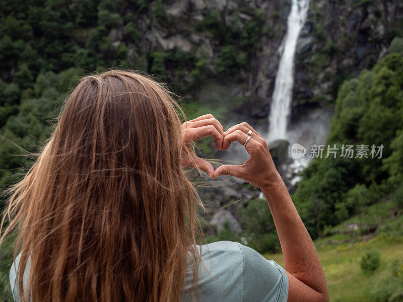 女人热爱自然，她用双手在瀑布上做了一颗心