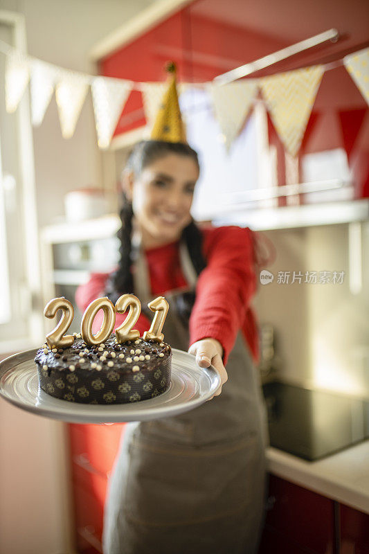 年轻美丽的女人庆祝圣诞节，拿着巧克力蛋糕和蜡烛形状的数字2020，代表即将到来的新年