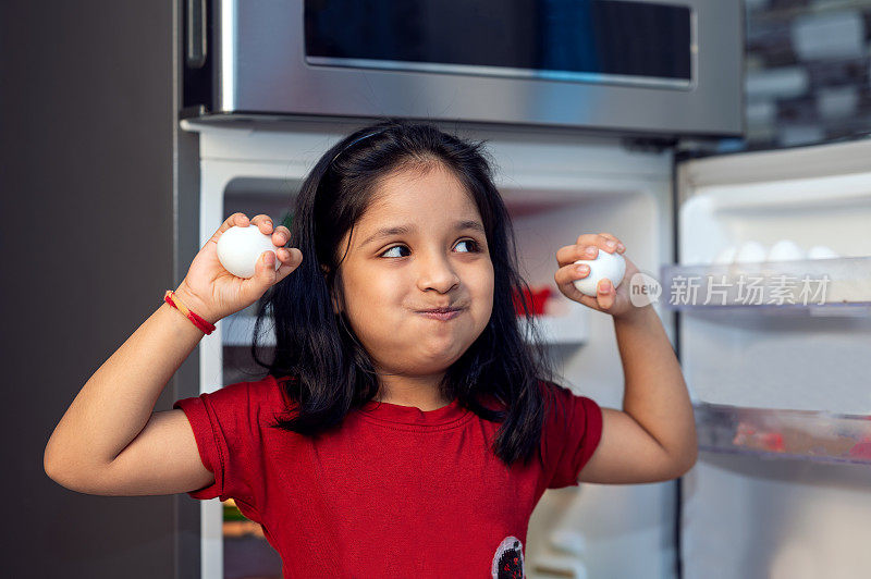 小女孩从冰箱里拣鸡蛋