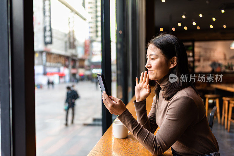 年轻的亚洲女性在咖啡店里使用智能手机