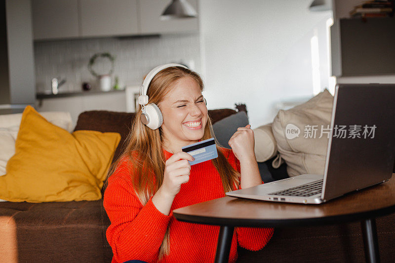 一个年轻的女人正在用信用卡在家里进行网上购物