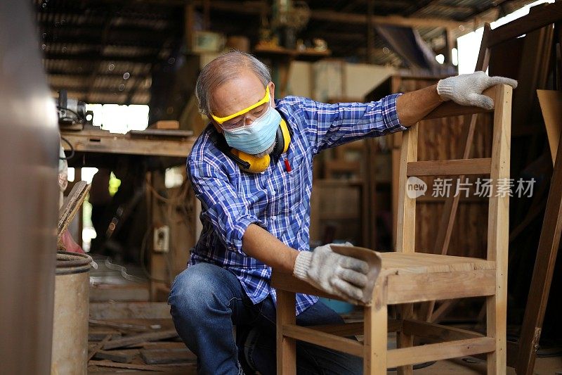 亚洲资深木匠正在他自己的车库风格的车间修理木椅在退休年龄的爱好