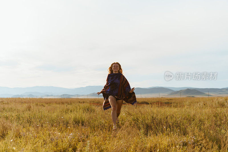 女孩在操场上奔跑，头发长出来了。山脉和日落。俄罗斯西伯利亚
