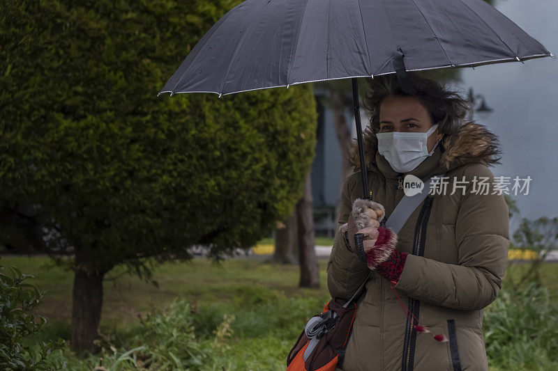 一个女人在阴雨的冬天在街上等待