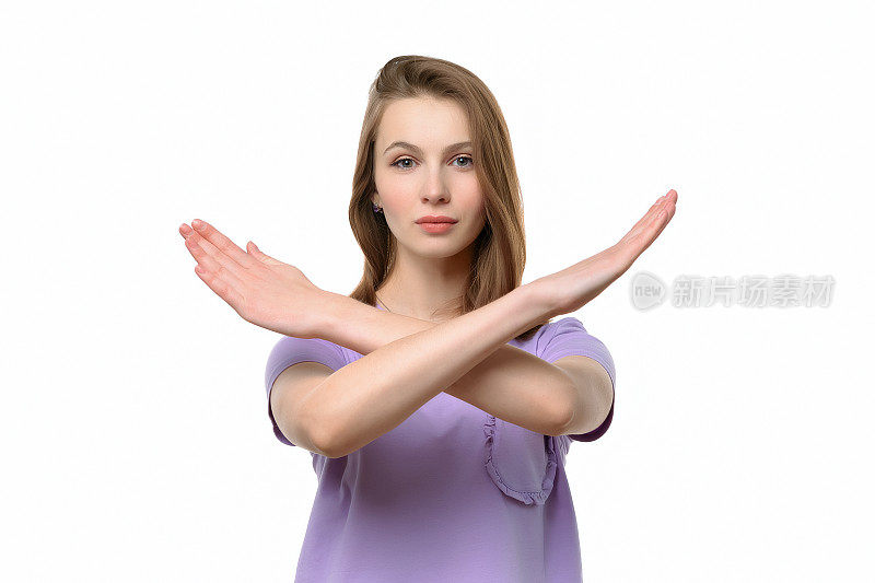 严肃的年轻女子双手交叉，对着镜头做停顿手势。否定概念