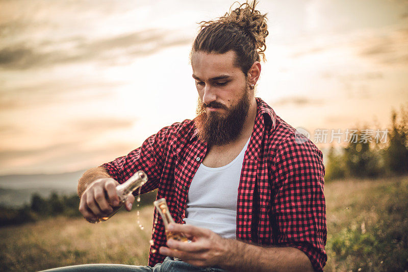 自然的守护者。一个在山上的男人，一个伐木工人，喝着自制的白兰地，吃着自制的食物，而在他身后是美丽的日落，休息辛苦的工作。