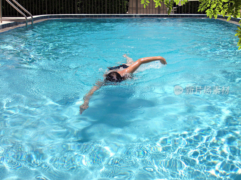 年轻女子在游泳池游泳