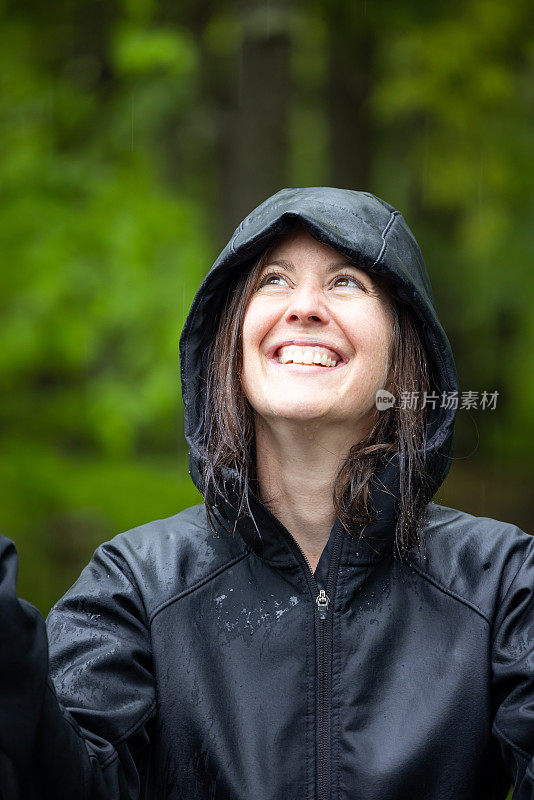 穿着雨衣在森林里徒步旅行的快乐女人