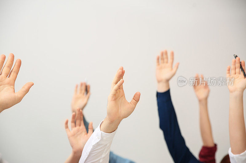 在商务培训中，人们举手提问，白色背景，特写镜头