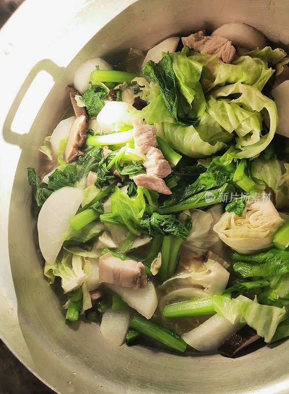 在炉子上的蔬菜炖汤中加入卷心菜-食物准备。