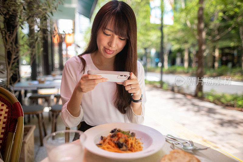 一名日本女子为了写博客，在露台咖啡馆拍摄午餐