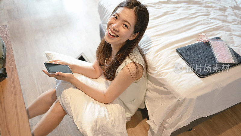 微笑开朗的亚洲千禧一代和Z世代亚洲女性使用手机外卖网站阅读评论从她的卧室