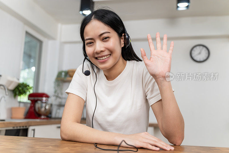 有吸引力的年轻亚洲女人视频通话，挥手和看着相机。