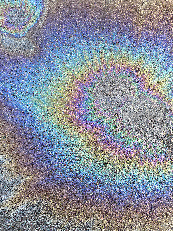 汽车燃油和水在柏油路面上溢出的图像，汽油油在柏油路面上形成的彩虹效果，高架视图