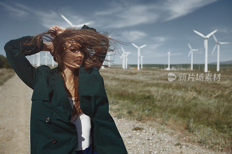 女人蓬乱的长发旁边的风力发电机随风吹动