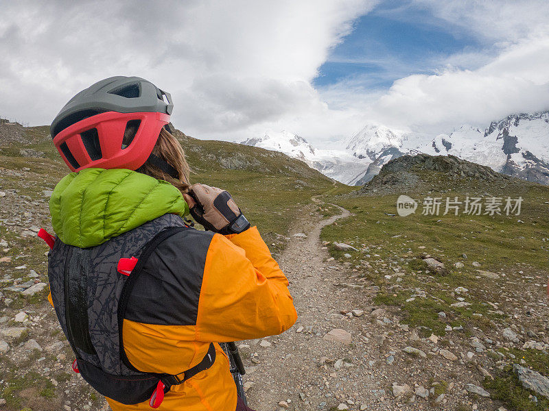 山地自行车手在土路上，远处有冰川