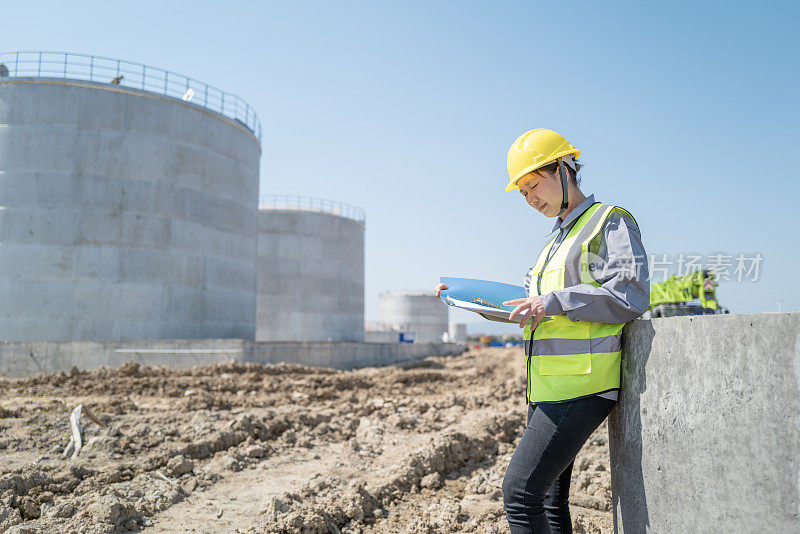 一名中国女建筑工程师在一个未完工的建筑工地检查数据