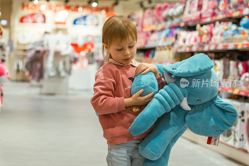 白人小女孩在婴儿用品商店里摆弄新玩具。