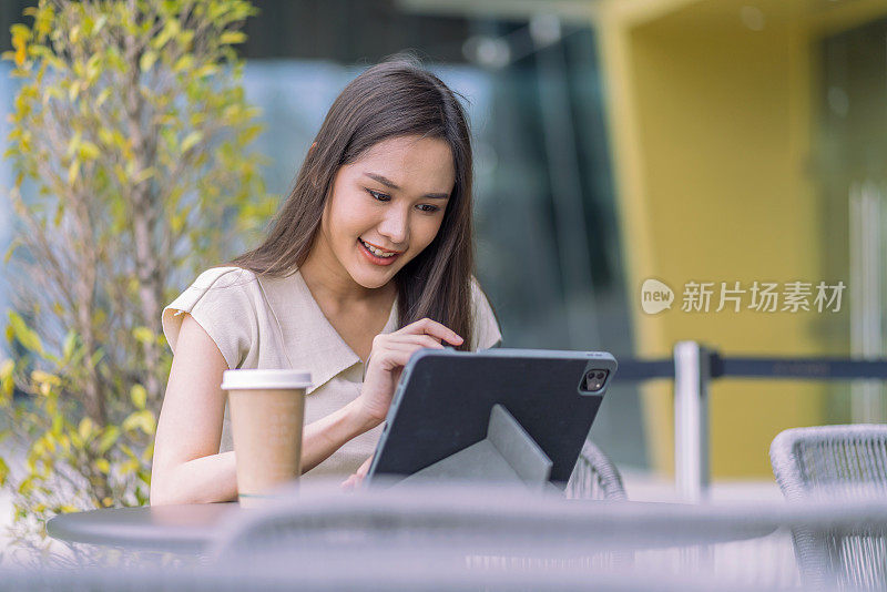 亚洲女性数字游牧民幸福自由快乐微笑工作使用平板电脑在花园户外，亚洲女性自由放松休闲工作任何地方工作和旅游与花园散景背景