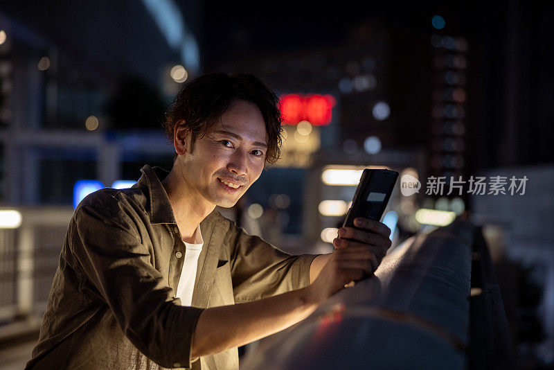 男子夜间在人行天桥上使用智能手机的肖像