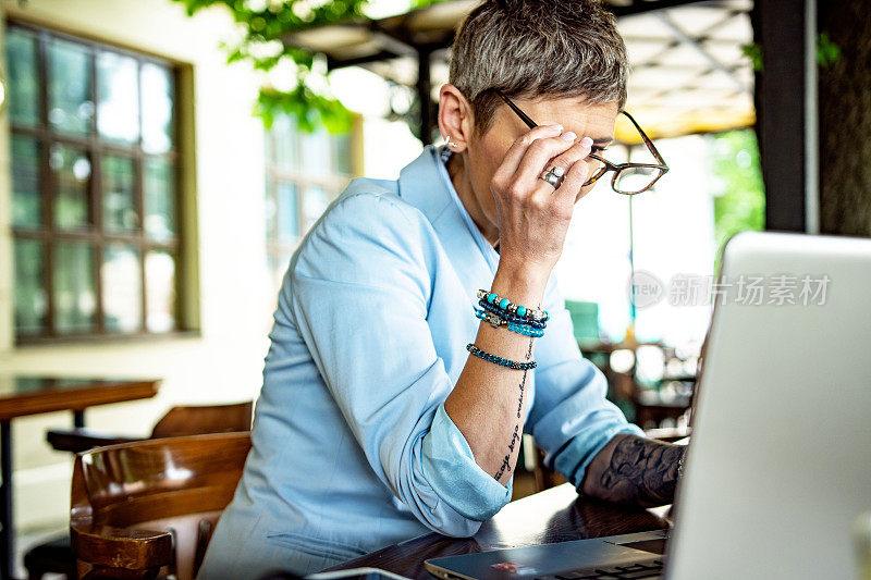 成熟女性坐在咖啡店用笔记本电脑网购