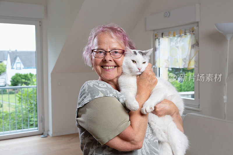 老妇人高兴地抱着她的宠物主人白猫