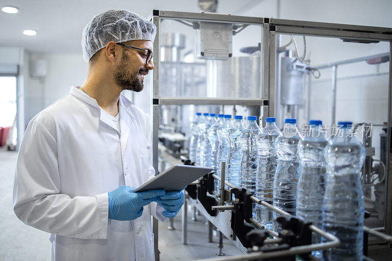 在装瓶厂，技术员穿着无菌制服和发网检查水的生产。