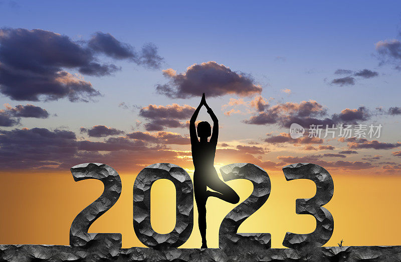 2023年新年快乐，女性在日落时练习瑜伽的剪影