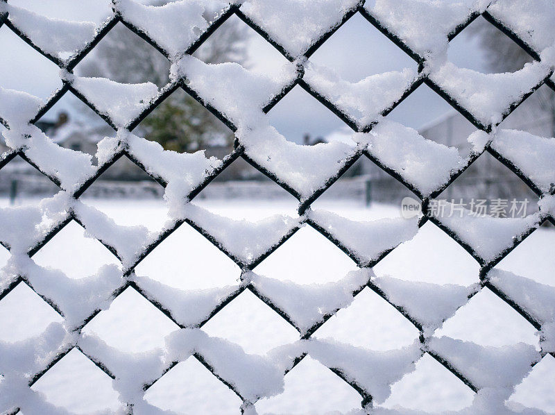铁丝栅栏和网球场上的雪