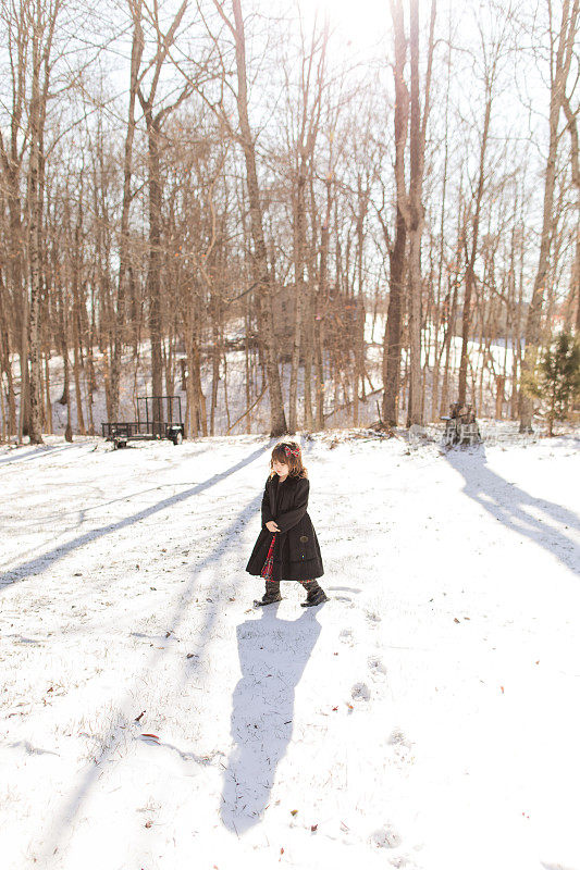 2022年12月，俄亥俄州杰克逊，一个3岁的古巴裔美国学步女孩在寒冷的雪天穿着外套、靴子和蝴蝶结，在新鲜的白色蓬松的雪中度过圣诞节