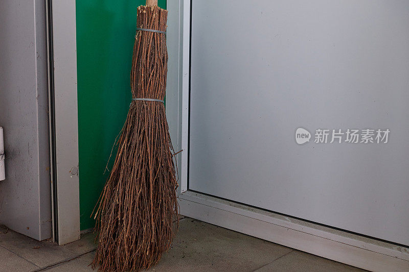 房间的角落里放着一把树枝做的扫帚，扫帚的柄是木制的。