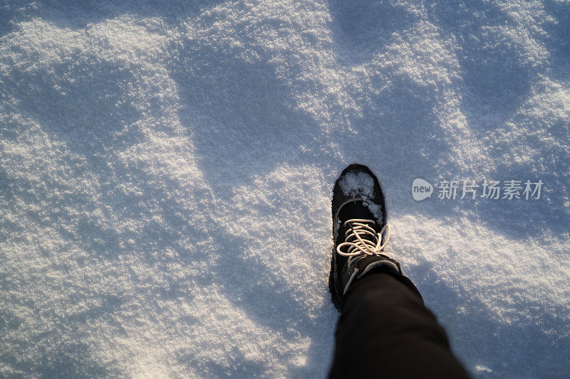 一条腿穿着冬靴走在雪地上