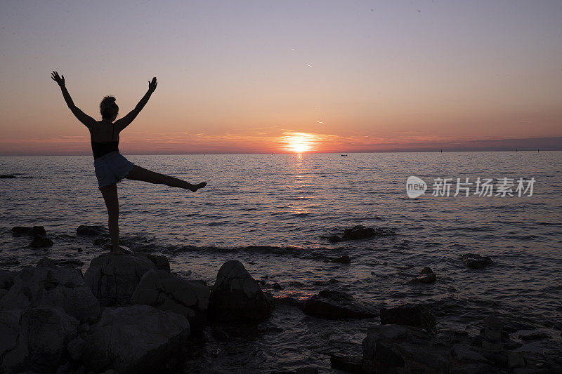 女人站在海边欣赏壮丽的日落