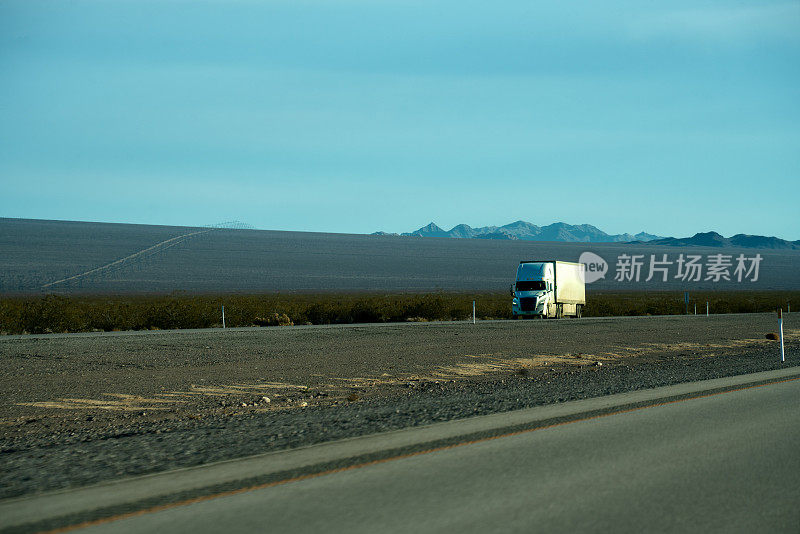 一辆白色半挂车在两车道公路上运输石油，天空中有美丽的云