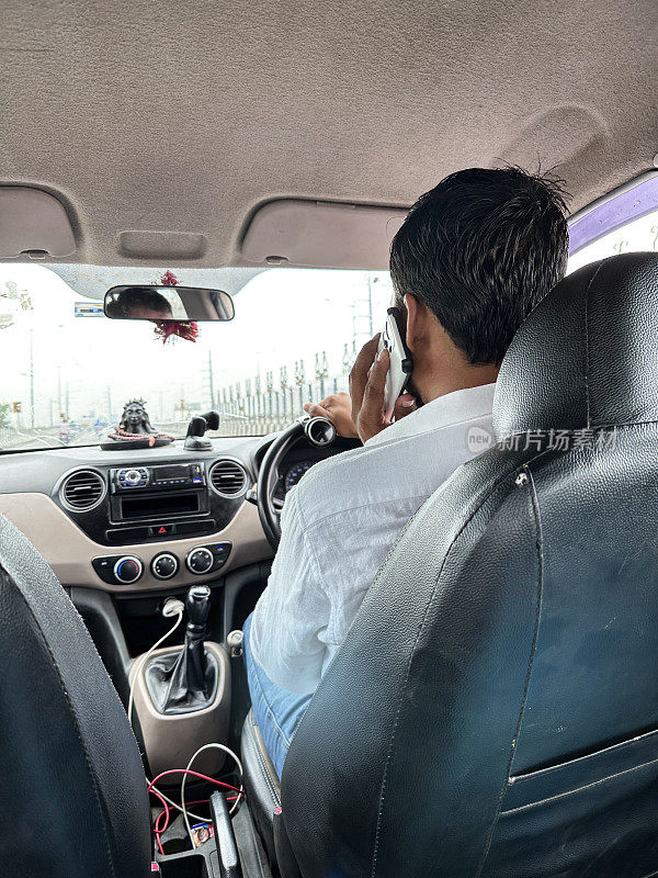 印度男子在高速公路上用手机驾驶私人出租车的形象，危险的驾驶概念，司机使用手机，后视图，焦点在前景