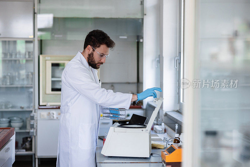 一位年轻的男科学家正在实验室里使用离心机