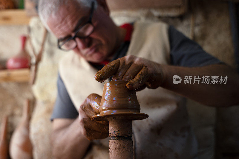 一位老人正在制作一个陶杯