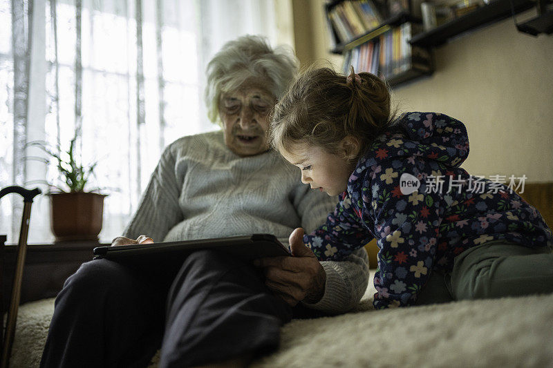 曾祖母给小女孩读电子故事。