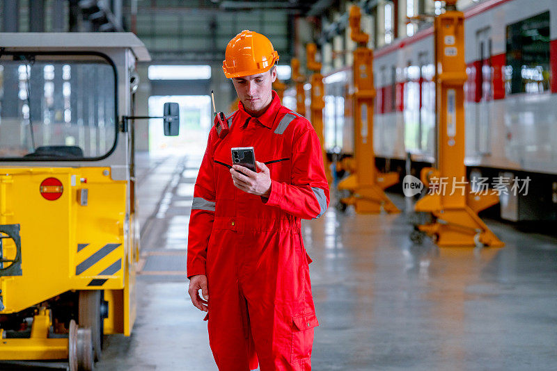 电气或地铁工厂的专业技术工人站着看手机。工业工作场所中沟通的概念。