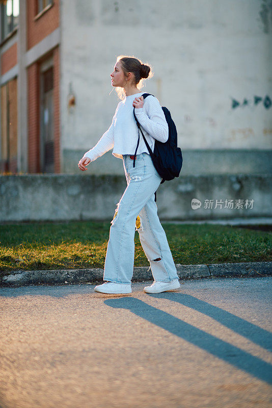 一个美丽的欧洲少女，在夕阳下放学回家，背着她的背包