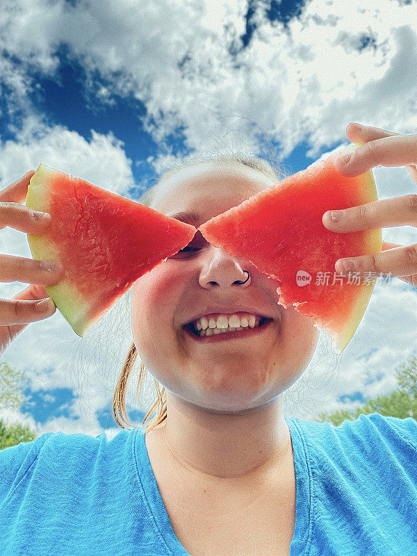 可爱的少女在夏天在户外享受西瓜。