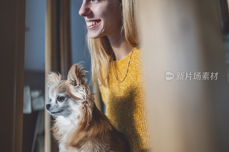 一个女人带着一只吉娃娃狗在客厅里