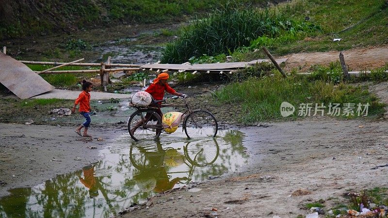 一个印度人带着他的自行车穿过脏水