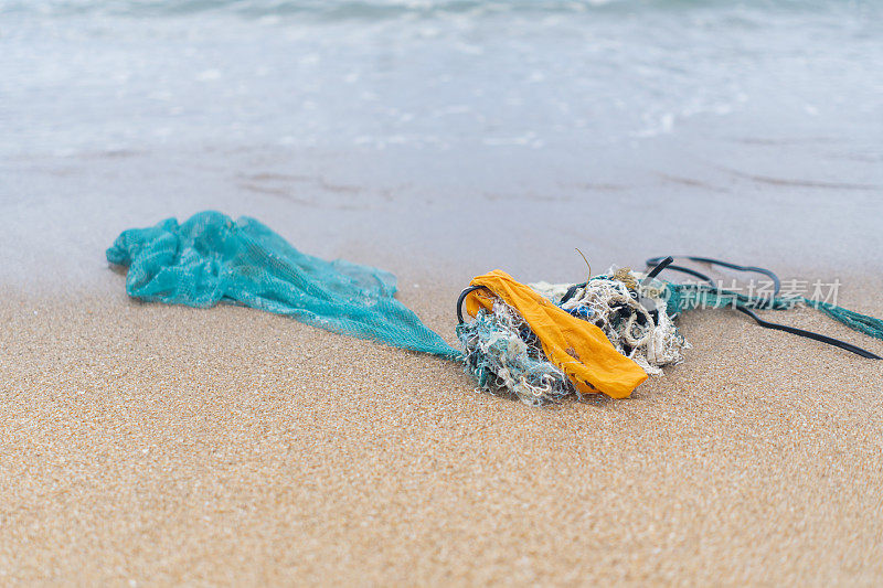 人类在海岸线上捕鱼后在海岸上留下渔网，导致环境问题和海洋中塑料的严重污染和微塑料的产生。