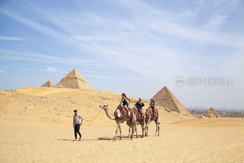 游客骑骆驼在埃及沙漠和参观金字塔在开罗。