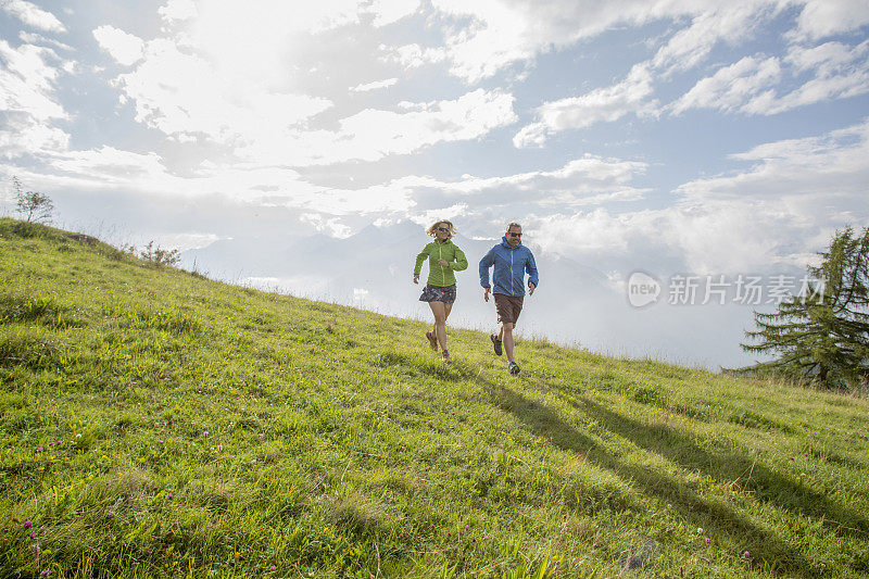 跑步者爬上山坡，穿过草地