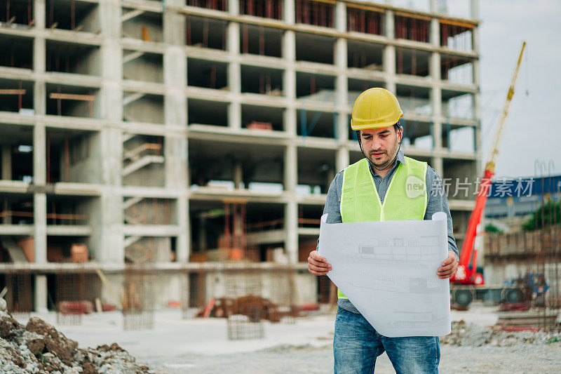 年轻建筑师在建筑工地设计蓝图。